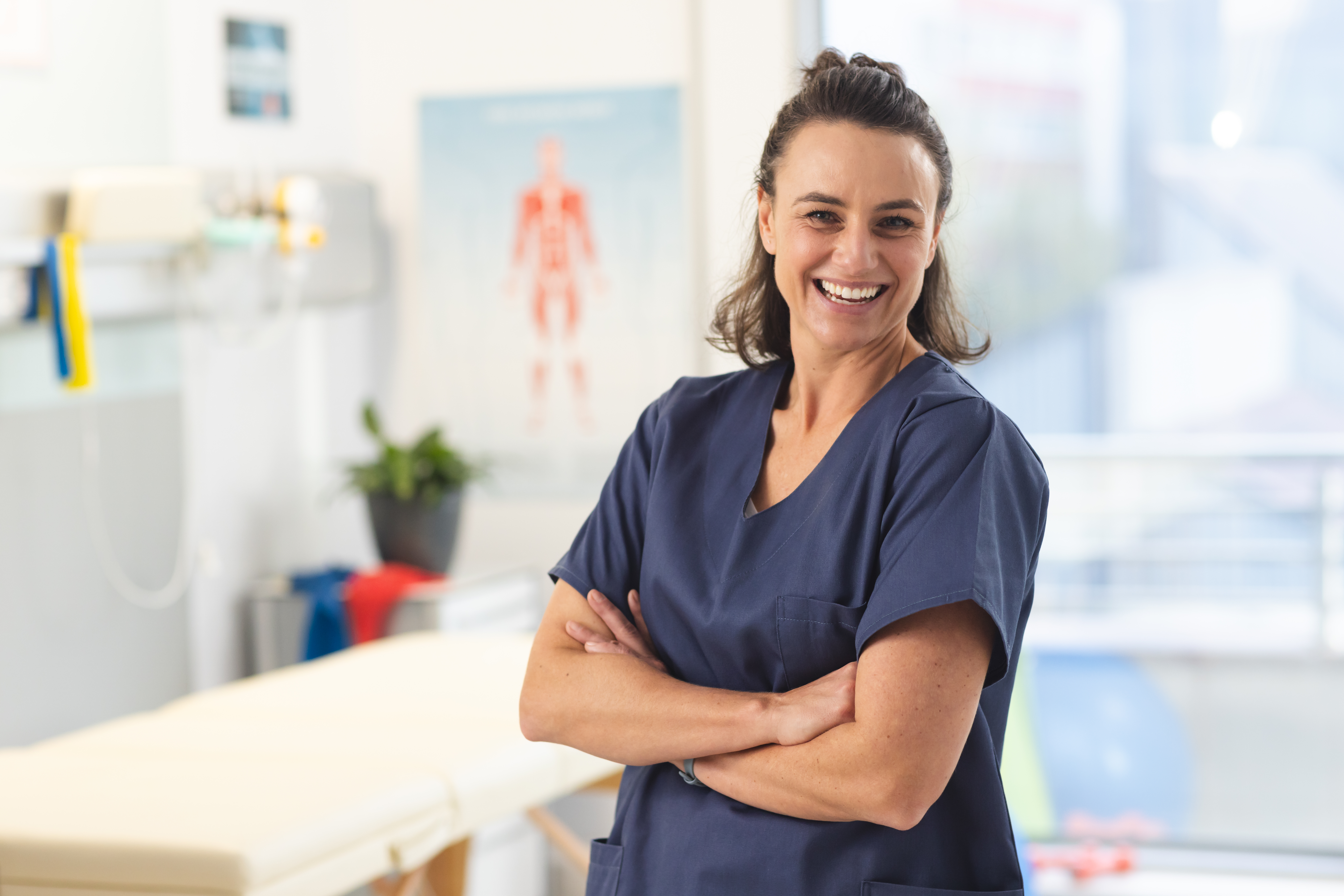 Portrait of happy female caucasian physiotherapist wearing scrubs at hospital. Hospital, physiotherapy, work, medicine and healthcare, unaltered.
