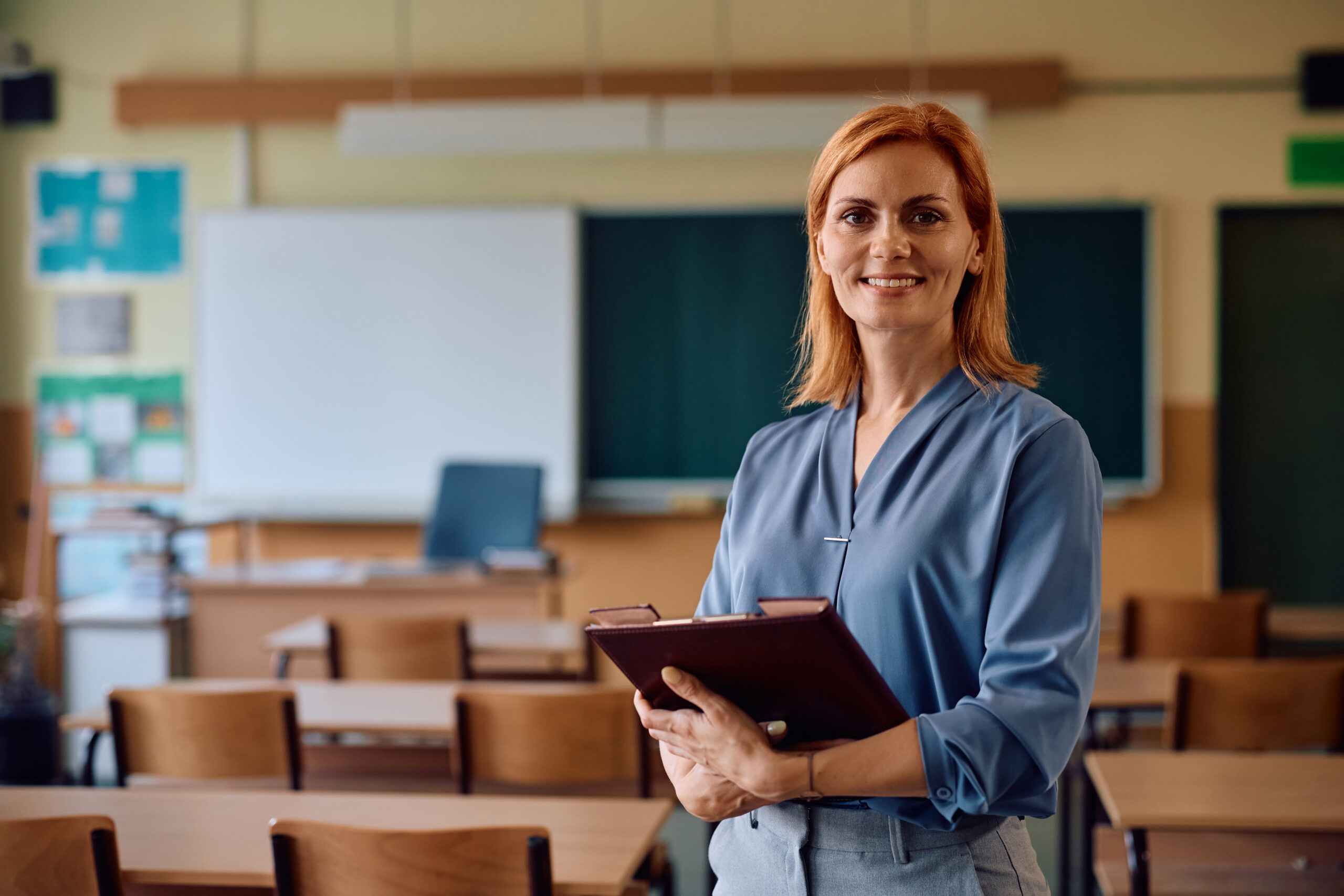 Portrait of happy female teacher in the classroom looking at camera.
